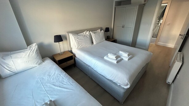 Een hotelkamer met twee bedden, een nachtkastje met een lamp, een garderobe en een radiator.