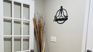 A hallway with a white door, a potted plant, and a wall-mounted sign. - Marvelous Townhome + Car Charger & Near Events (Atlanta)