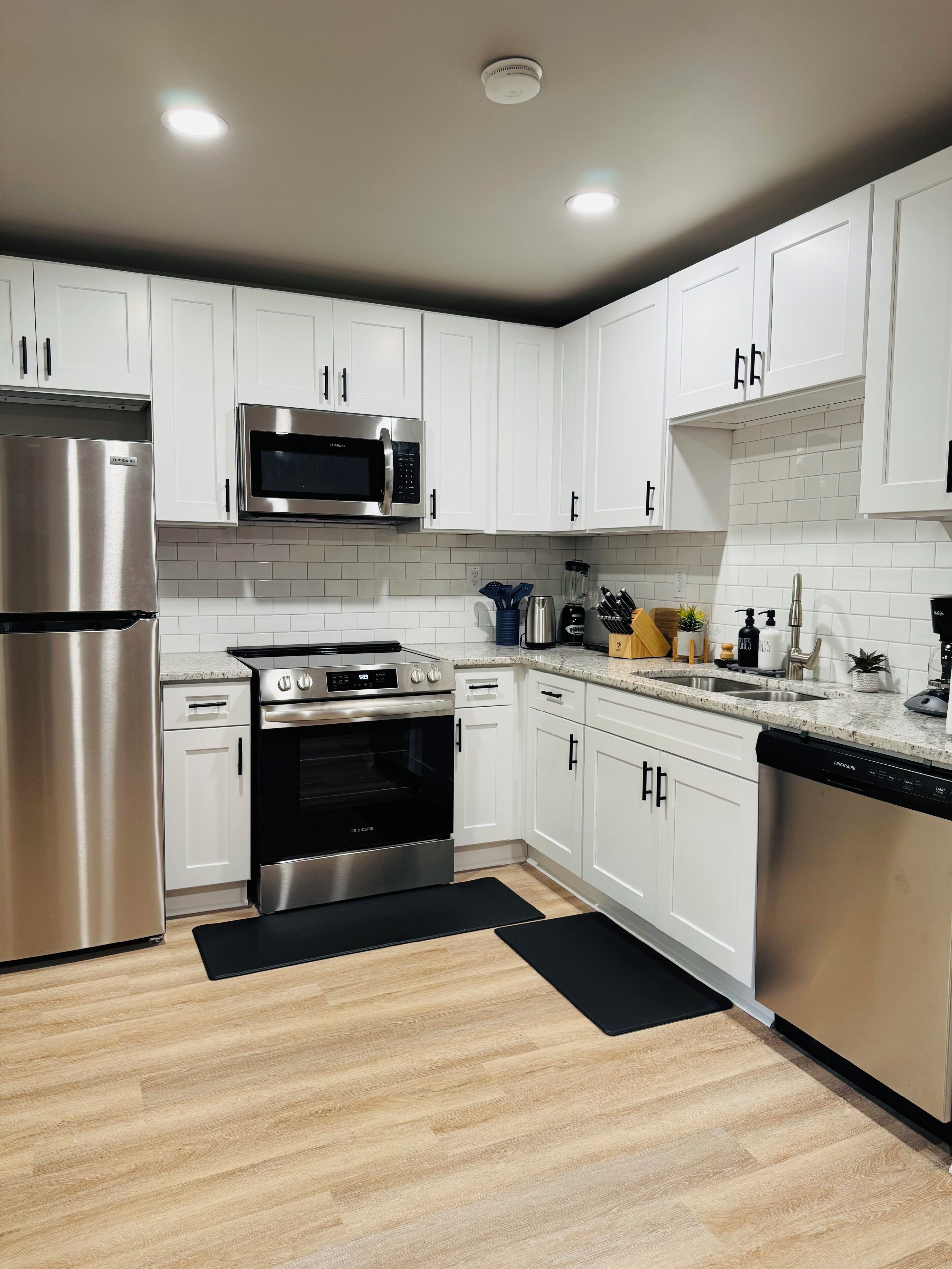 Una cocina moderna con armarios blancos, electrodomésticos de acero inoxidable y encimera negra.