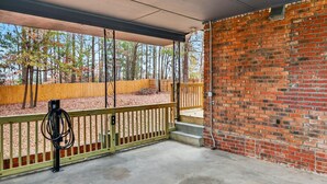 A covered outdoor area with a brick wall, a wooden fence, and a concrete floor. - Marvelous Townhome + Car Charger & Near Events (Atlanta)