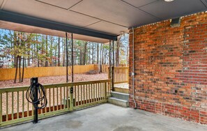 A covered outdoor area with a brick wall, a wooden fence, and a concrete floor. - Marvelous Townhome + Car Charger & Near Events (Atlanta)