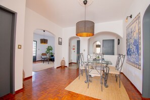 A spacious dining area with a glass table and metal chairs, a hanging light fixture, and a decorative tile wall. - Casa do Livramento in Carvoeiro (Lagoa)