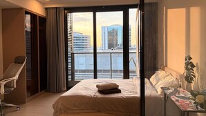 A hotel room with a bed, a desk, a chair, and a large window with a city view. - BIG Standing Desk with w/Pool, Spa, Gym, near MRT (Huai Khwang)