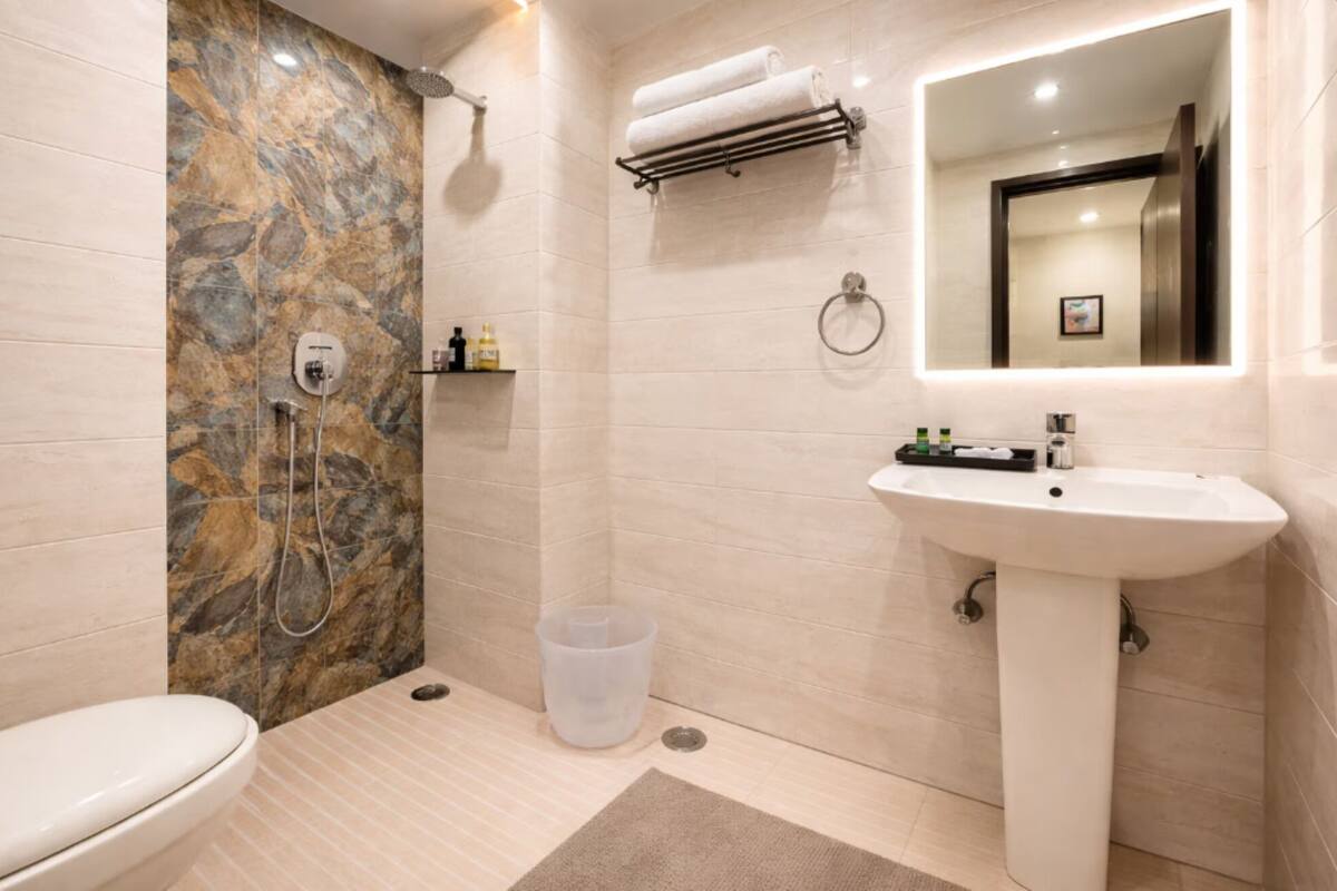 A bathroom with a shower, toilet, sink, and a mirror.