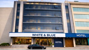 A hotel with a modern facade, large windows, and a sign reading 'WHITE & BLUE HOTEL'. - OPO ALPINE TREE (New Delhi)