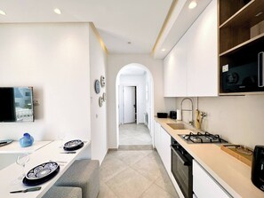 Eine moderne Küche mit Essbereich, einem an der Wand montierten Fernseher und Blick in den Wohnbereich.