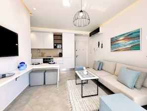 Eine moderne Wohnung mit Küchenzeile, Essbereich, Sofa und Fernseher.