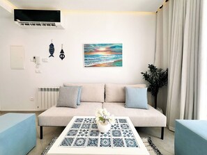 Ein Wohnzimmer mit einer Couch, einem Couchtisch mit einer Pflanze, einem Gemälde und einer Heizung.