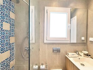 Ein modernes Badezimmer mit Dusche, Waschbecken und Spiegel.