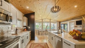 Eine moderne Küche mit Holzboden, großen Fenstern und einer zentralen Kochinsel mit Obst.