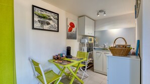 A compact kitchen with a dining area, white cabinets, a microwave, and a small refrigerator.