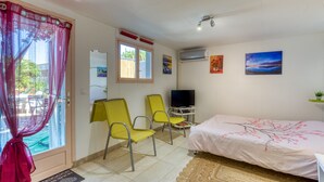A bedroom with a bed, two chairs, a TV, and artwork on the wall.