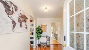 A hallway with a wooden floor, a globe map on the wall, a potted plant, and a door with frosted glass. - Stunning fall foliage views with EV charger close to Cooperstown (Sharon Springs)