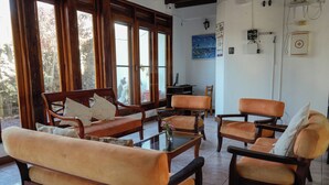 Ein Zimmer mit einer Couch, Sesseln, einem Couchtisch und großen Fenstern.