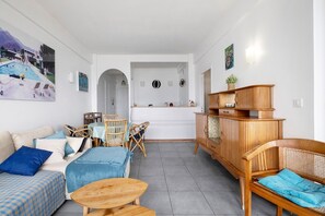 Ein Wohnzimmer mit einer Couch, Sesseln, einer Holzkabine und einem Essbereich mit Tisch und Stühlen.