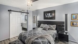 Camera da letto con un letto, una ventola a soffitto, un armadio e un quadro appeso al muro.