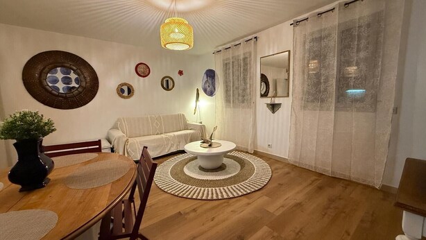 A living room with a round coffee table, a sofa, a dining table with chairs, a vase with a plant, and a hanging light fixture. - Flat « Étoile de Mer » Cannes center (Cannes)