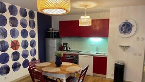 A compact kitchen with a dining area, a refrigerator, a sink, and a trash bin. - Flat « Étoile de Mer » Cannes center (Cannes)