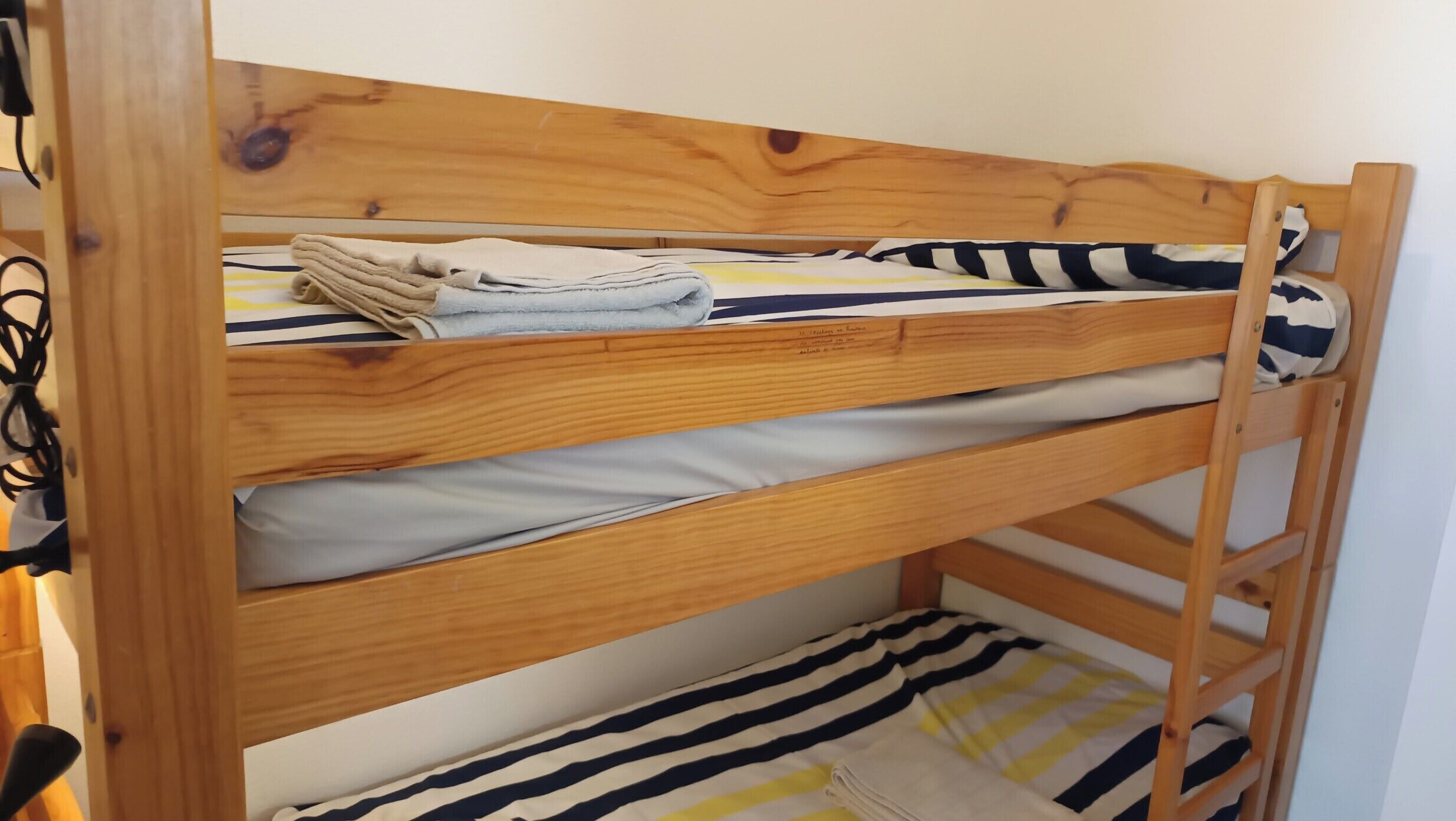 Ein Stockbett mit zwei Schlafstellen, jeweils mit Kopfkissen und Decke.