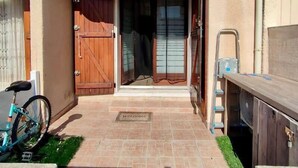 Un patio con un felpudo, una puerta de madera y una bicicleta.