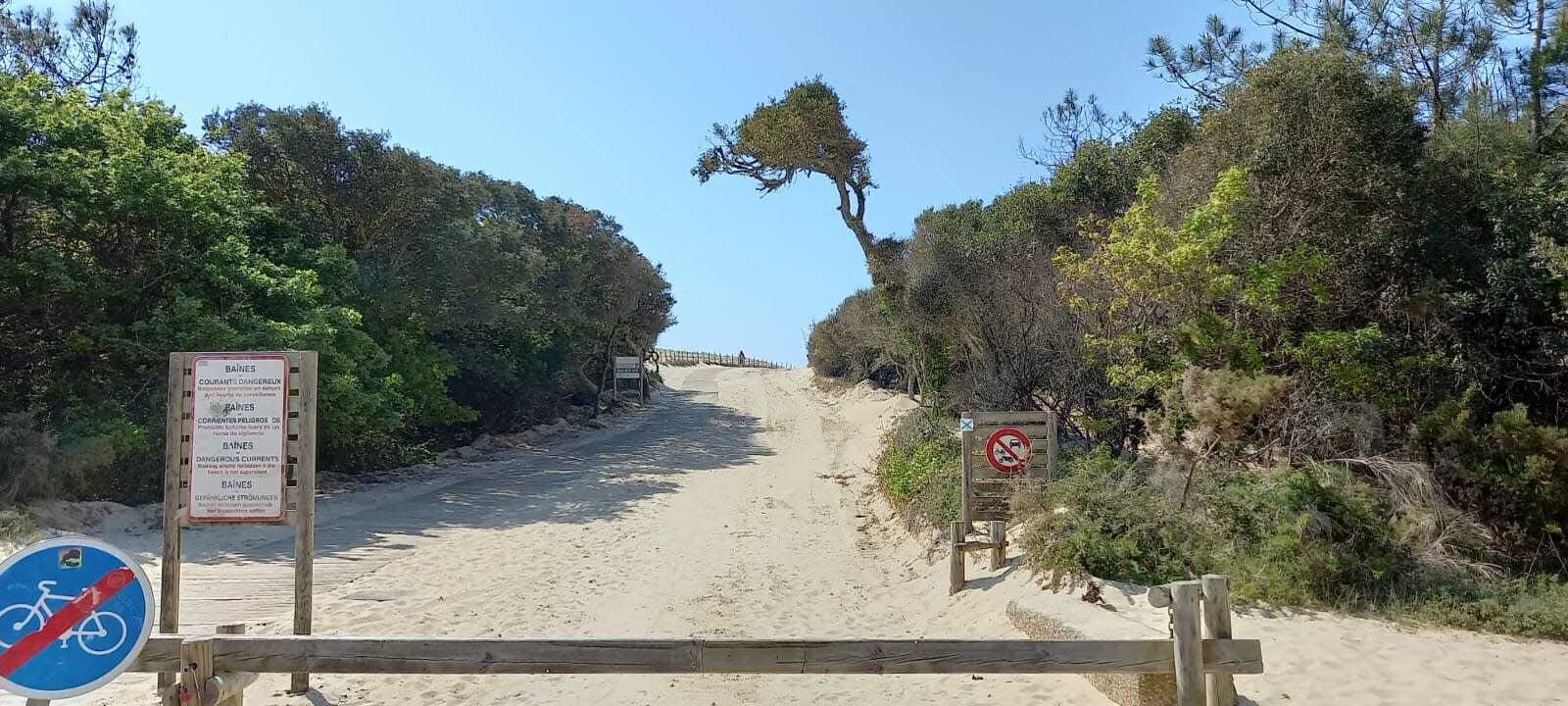 A sandy beach path with signs indicating 'BAINES' and 'COURANT D'ENGRASSON'.