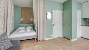 A bedroom with a bed, a bedside table, a mirror, and a wardrobe.