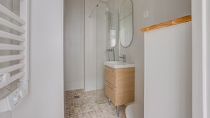 A bathroom with a shower, a sink, a mirror, and a toilet.