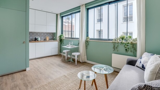 A compact living space with a kitchenette, a dining area, and a seating area with a sofa and two small tables.