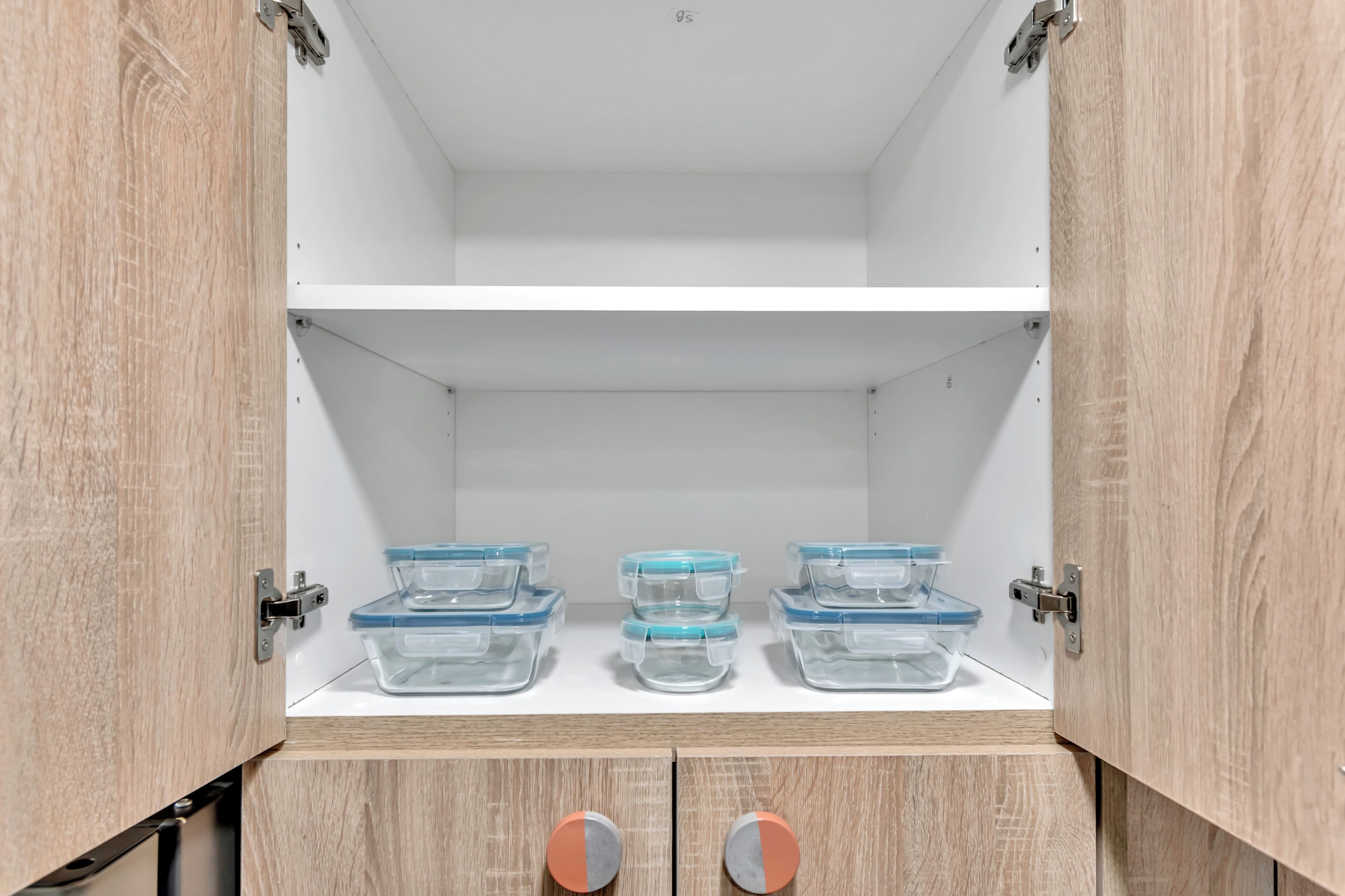 Ein Holzschrank mit drei durchsichtigen Aufbewahrungsbehältern auf der obersten Ablagefläche.