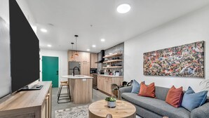 Un salon moderne avec un canapé gris, une table basse et un téléviseur posé sur un meuble en bois.