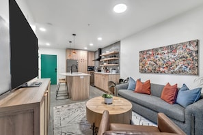 Una sala de estar moderna con un sofá gris, una mesita de centro y un televisor sobre un mueble de madera.