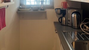 A compact kitchen with a window, a kettle, a toaster, and a sink. - Top location in Brissago 2 room apartment with private beach access. Dogs allowed (Brissago)