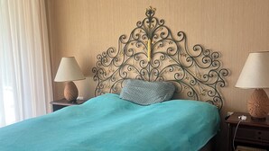 A hotel room with a bed, two bedside tables with lamps, a decorative metal headboard, and a window with curtains. - Top location in Brissago 2 room apartment with private beach access. Dogs allowed (Brissago)