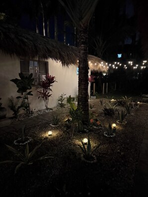A thatched-roof structure with a garden, illuminated by string lights. - Casa Brisa 2BR Treehouse Villa w/Pool-Breezy Open-Air Balcony in ProCab Cabarete (Cabarete)