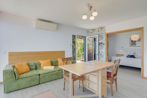 Una sala de estar moderna con un sofá verde, una mesa de comedor de madera y sillas.