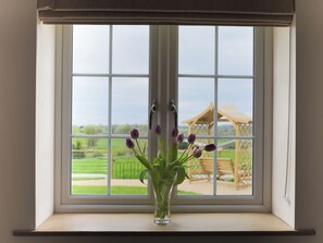 A window with a clear view of a garden and a wooden structure. - Stanbridge Cottage (Malmesbury)