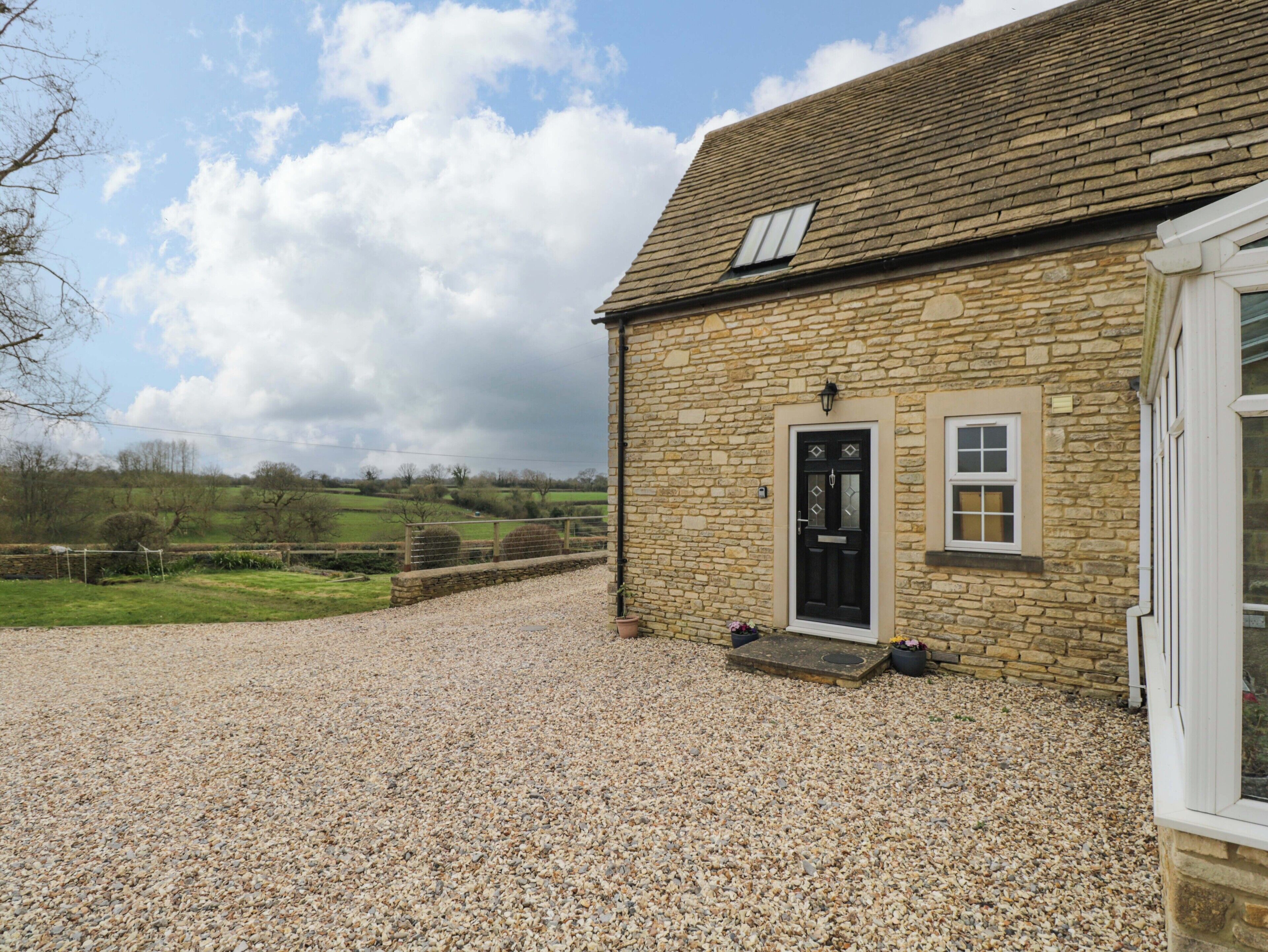 A stone building with a gravel driveway, a black door, and a small window.