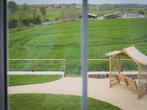 A view of a green field with a wooden structure and a metal fence. - Stanbridge Cottage (Malmesbury)