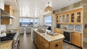 Una cocina moderna con una isla central, armarios de madera y vistas al océano.