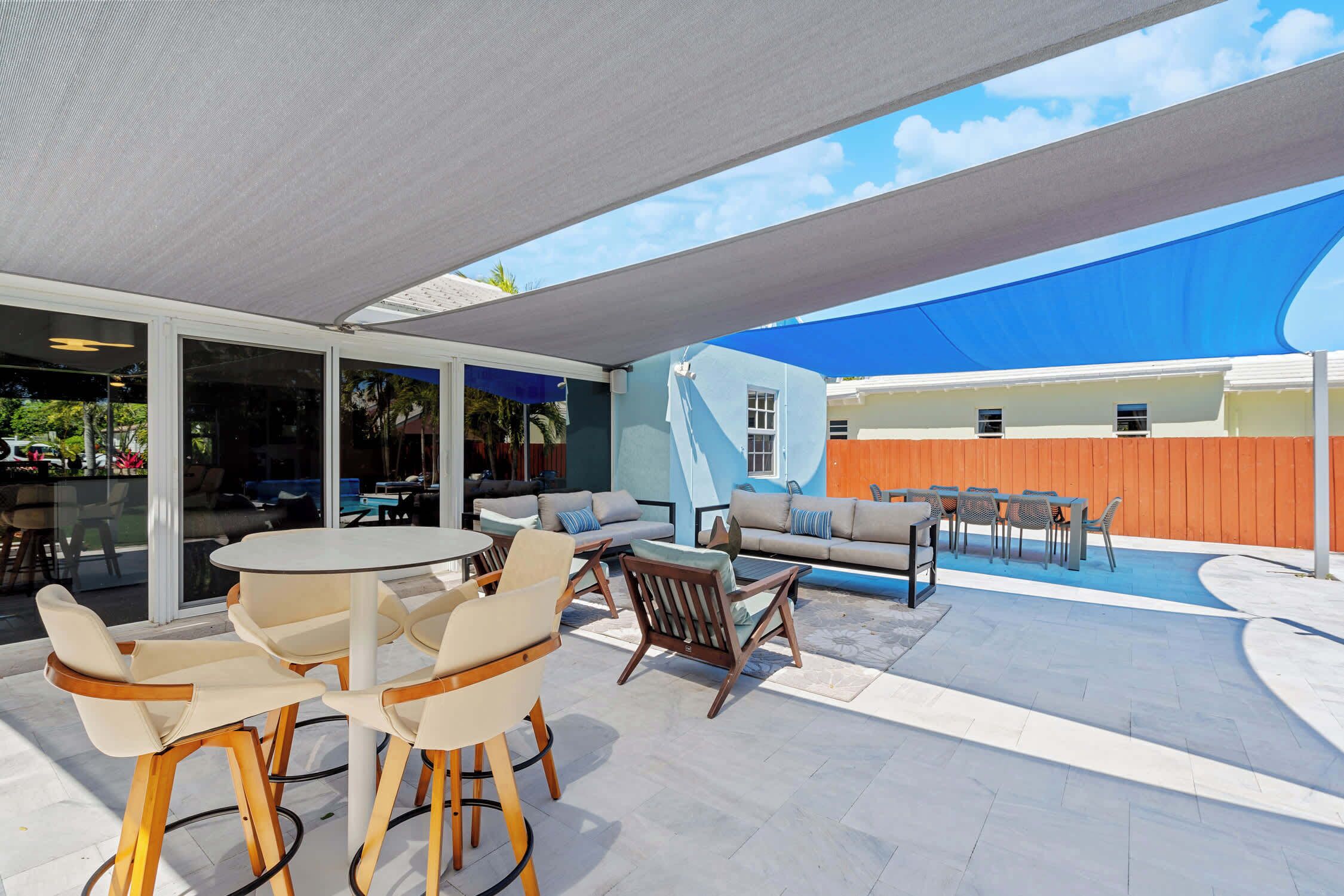 Un patio exterior con mesas y sillas redondas, un sofá y una zona de piscina.