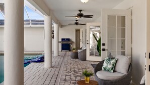 A covered patio area with a pool, wicker furniture, ceiling fans, and a view of the water. - 4-bedroom house in amazing Punta Gorda with cool vibes (Punta Gorda)