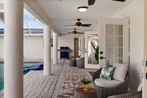 A covered patio area with a pool, wicker furniture, ceiling fans, and a view of the water. - 4-bedroom house in amazing Punta Gorda with cool vibes (Punta Gorda)