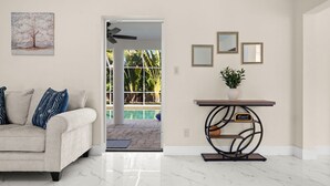 A living room with a sofa, a coffee table, a painting, and a view of a pool. - 4-bedroom house in amazing Punta Gorda with cool vibes (Punta Gorda)