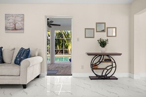 A living room with a sofa, a coffee table, a painting, and a view of a pool. - 4-bedroom house in amazing Punta Gorda with cool vibes (Punta Gorda)