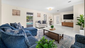 A living room with a sofa set, a coffee table, a TV, and a plant. - 4-bedroom house in amazing Punta Gorda with cool vibes (Punta Gorda)