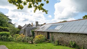 A stone building with a metal roof, surrounded by a grassy garden and trees. - Hideaway on Dartmoor, Uphill Coach House (Lustleigh)