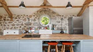 A kitchen with a stone wall, wooden beams, a large window, a stainless steel refrigerator, and a sink. - Hideaway on Dartmoor, Uphill Coach House (Lustleigh)