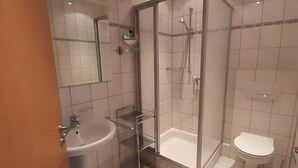 A modern bathroom with a glass-enclosed shower, a white sink, and a toilet.