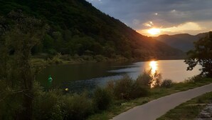 En flod med solnedgang, omgivet af bakker og grøn bevoksning.