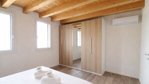 Un dormitorio con cama, dos toallas, un armario y un equipo de aire acondicionado.